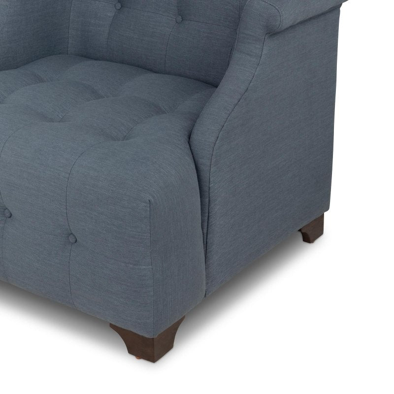 Close-up of the Scroll Arm heathered navy blue chair showing button tufting, the rolled arm and a wood block foot