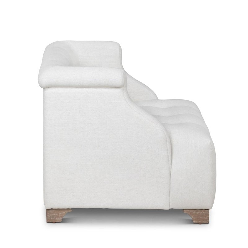Side profile of the Scroll Arm ivory chair showing its rolled arm, deep tufted seat and wood feet