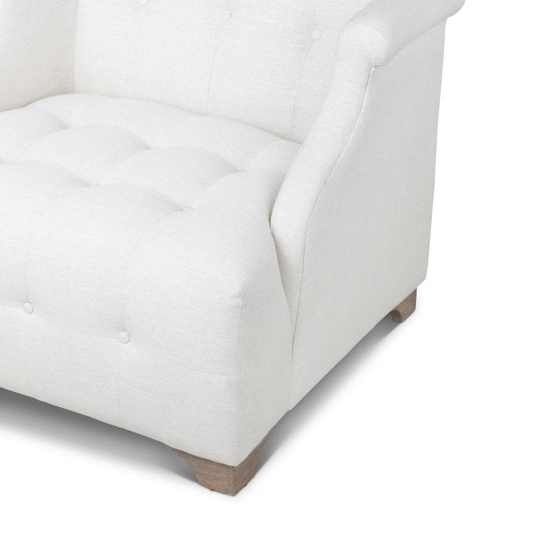 Close-up of the Scroll Arm ivory chair showing button tufting, the rolled arm and a wood block foot