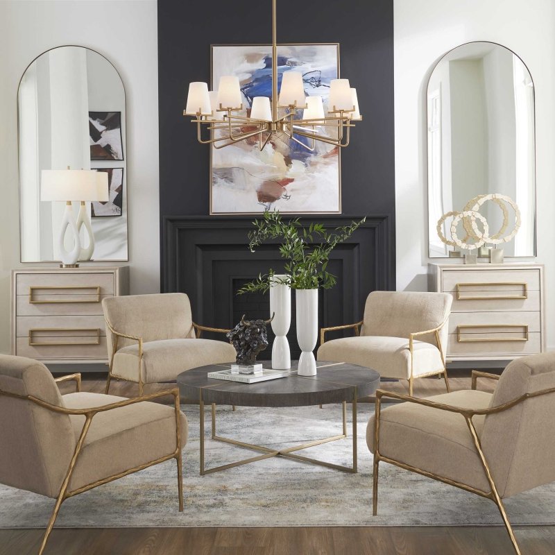 Curated modern home decor with gold chandelier, round coffee table, neutral accent chairs, and arched mirrors
