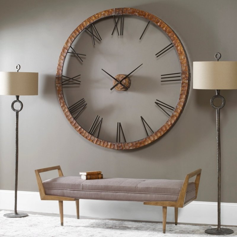 Large brass wall clock in minimalist living room with white walls and natural light