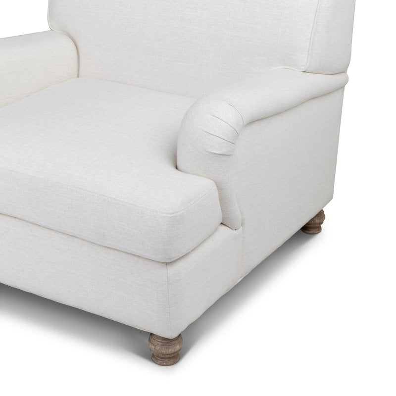 Close-up of the Kenwood ivory chair upholstery, loose seat cushion, rounded arm and turned wood foot