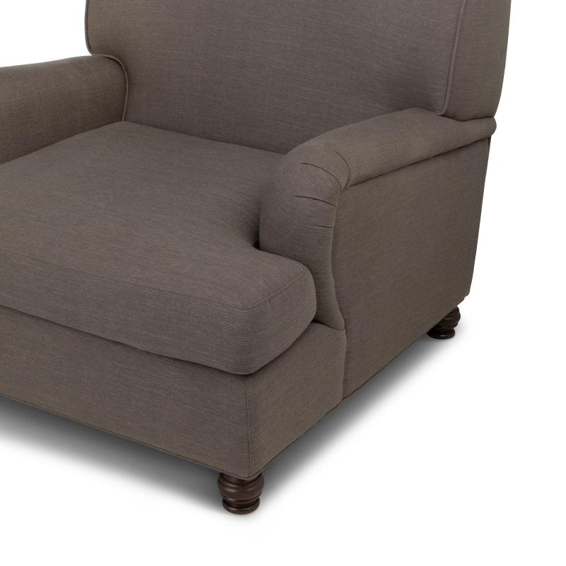 Close-up of the Kenwood mocha brown chair upholstery, loose seat cushion, rounded arm and turned wood foot
