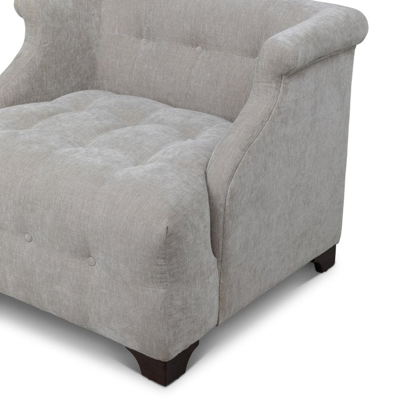 Close-up of the Scroll Arm putty gray chair showing button tufting, the rolled arm and a wood block foot