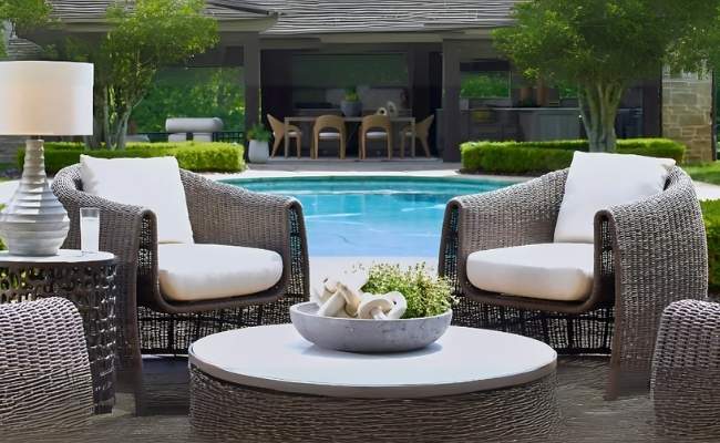 Outdoor patio furniture set with cushions by a poolside.
