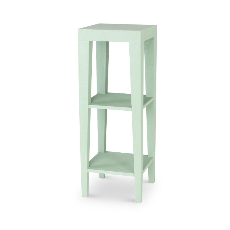 Three-quarter view of the Giraffe Leg pale Garden Retreat green faux raffia pedestal with two open shelves and tapered legs