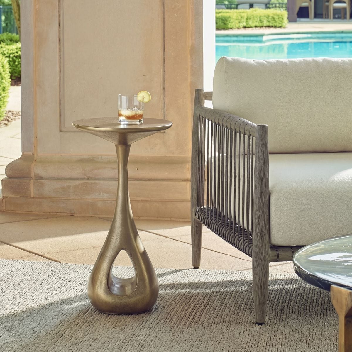 Tolstoy Antique Brass Indoor-Outdoor Accent Table styled in an outdoor setting